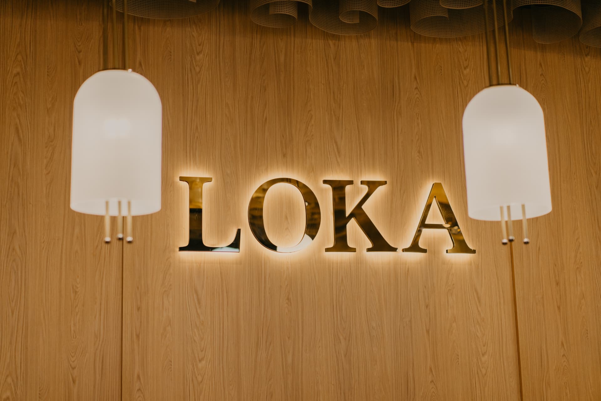 LOKA logo osvijetljen na drvenom zidu restorana