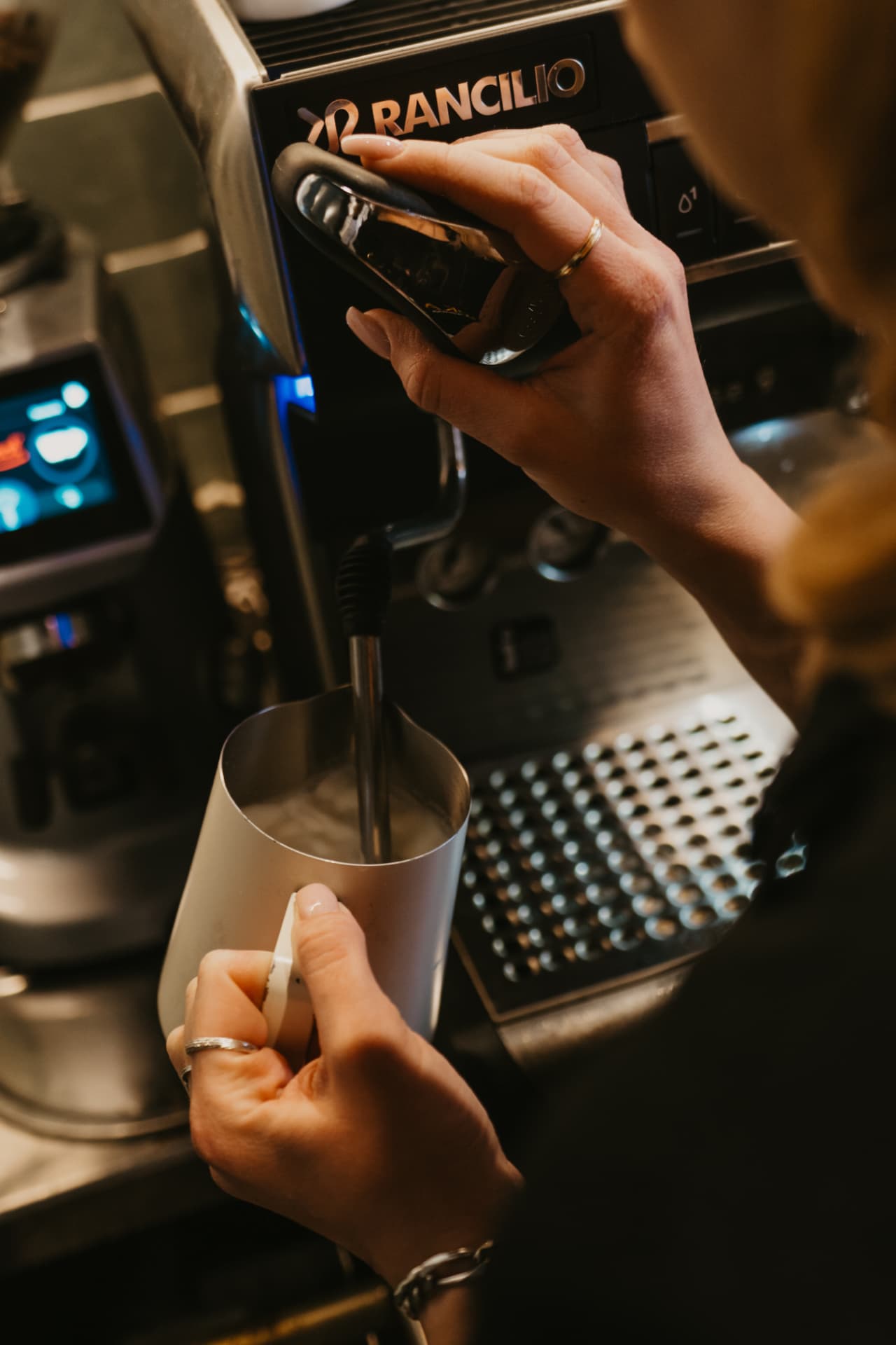 Barista pjeni mlijeko na espresso aparatu